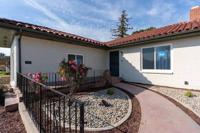 506 W Terrace Ave, Fresno, CA 93705 - property entrance with a tile roof, brick siding, and a chimney