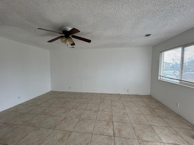 empty room featuring visible vents, ceiling fan, a textured ceiling, and light tile patterned flooring