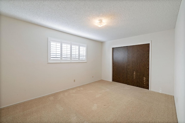 unfurnished bedroom featuring a textured ceiling, a closet, and carpet flooring