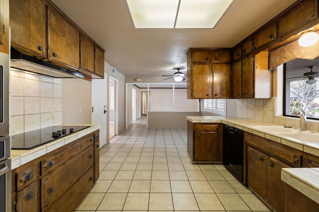 kitchen with tile counters, a ceiling fan, a sink, a peninsula, and black appliances