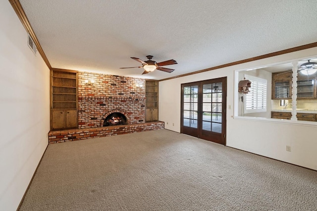 unfurnished living room with built in shelves, carpet, a fireplace, ornamental molding, and a textured ceiling