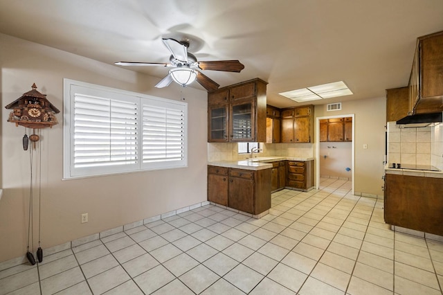 kitchen featuring brown cabinetry, backsplash, light countertops, and visible vents