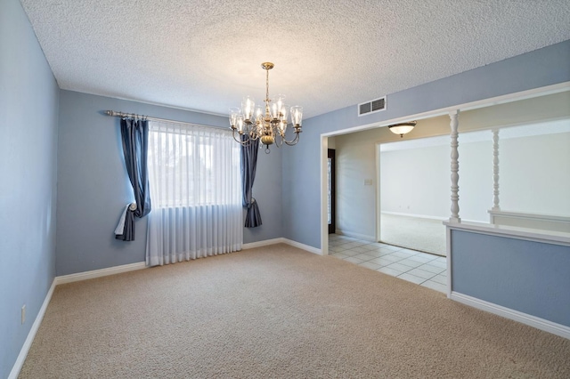 empty room featuring an inviting chandelier, visible vents, a textured ceiling, and light colored carpet