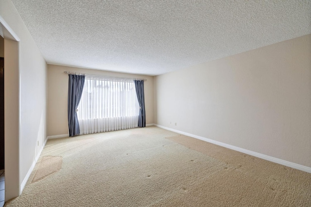 carpeted empty room featuring a textured ceiling and baseboards