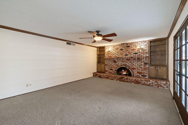 unfurnished living room with visible vents, ornamental molding, a textured ceiling, carpet flooring, and a fireplace