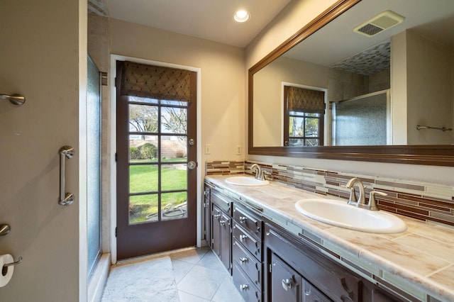 full bath with a stall shower, visible vents, decorative backsplash, and a sink