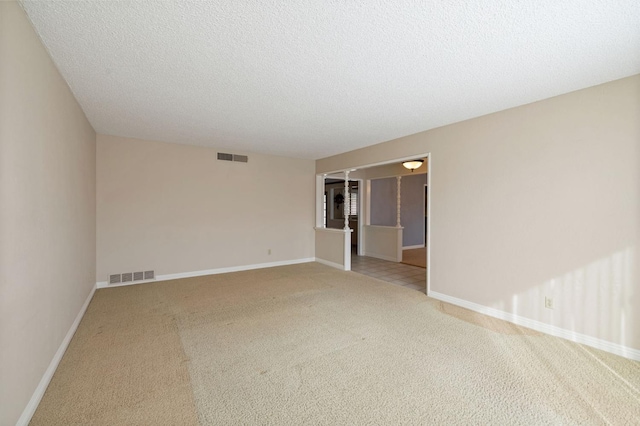 carpeted spare room featuring visible vents, a textured ceiling, and baseboards