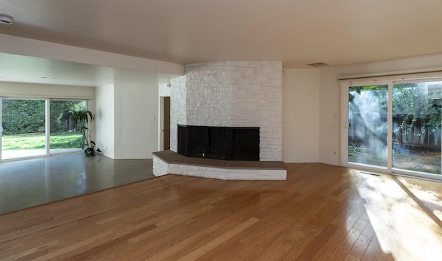 unfurnished living room with a wealth of natural light, a fireplace, visible vents, and wood finished floors