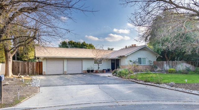 single story home featuring aphalt driveway, a front lawn, fence, and an attached garage