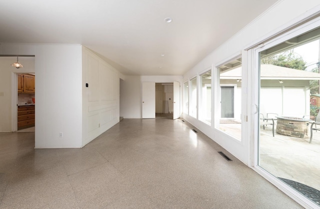 empty room featuring visible vents, crown molding, and speckled floor