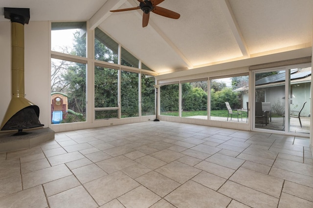 unfurnished sunroom featuring a wood stove, ceiling fan, and lofted ceiling with beams