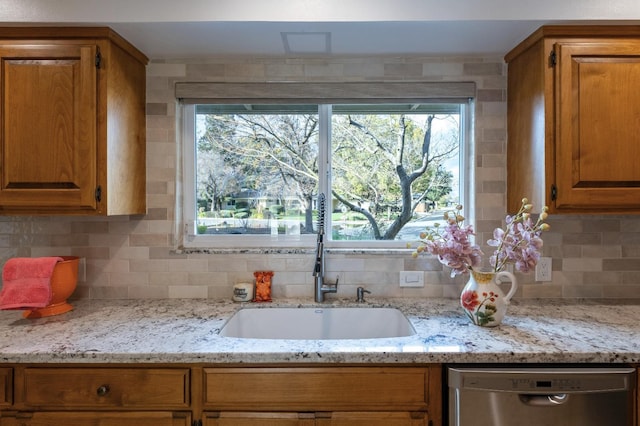 kitchen featuring a sink, backsplash, brown cabinets, and stainless steel dishwasher