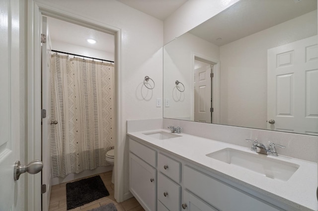 full bathroom with curtained shower, a sink, toilet, and double vanity