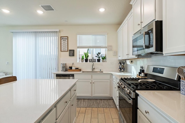 kitchen featuring light countertops, visible vents, appliances with stainless steel finishes, white cabinets, and a sink