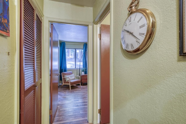 hallway with a textured wall and wood finished floors