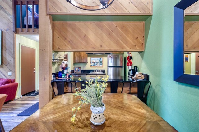 dining space featuring wooden walls, wood finished floors, and a textured wall