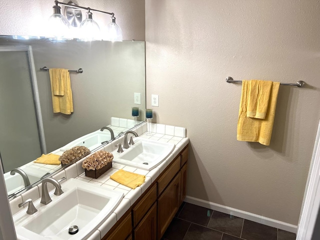 full bath with tile patterned floors, a sink, baseboards, and double vanity