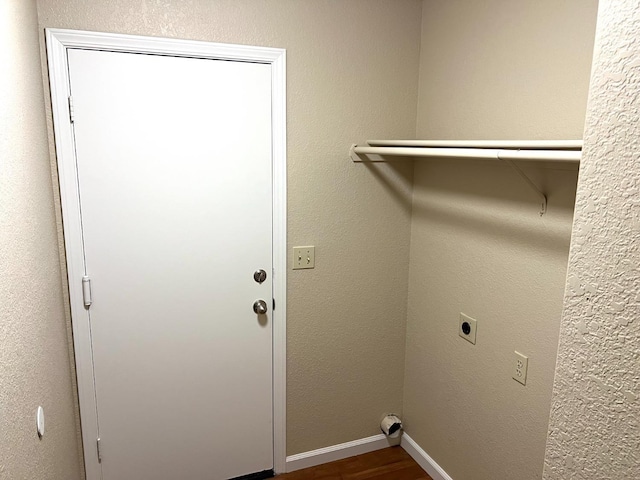 laundry area with a textured wall, laundry area, dark wood-style flooring, baseboards, and electric dryer hookup