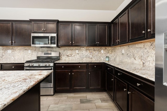 3384 Amanecer Ave, Clovis, CA 93619 - kitchen with stainless steel appliances, backsplash, dark brown cabinetry, light stone countertops, and wood finish floors