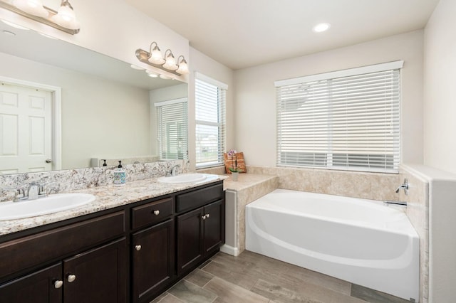 3384 Amanecer Ave, Clovis, CA 93619 - bathroom featuring a garden tub, wood finished floors, double vanity, and recessed lighting