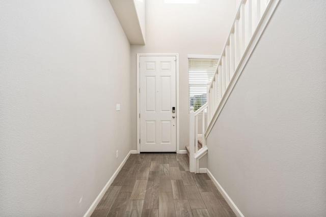 doorway featuring stairs, baseboards, and wood finished floors