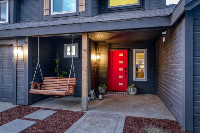 doorway to property with a porch and roof with shingles