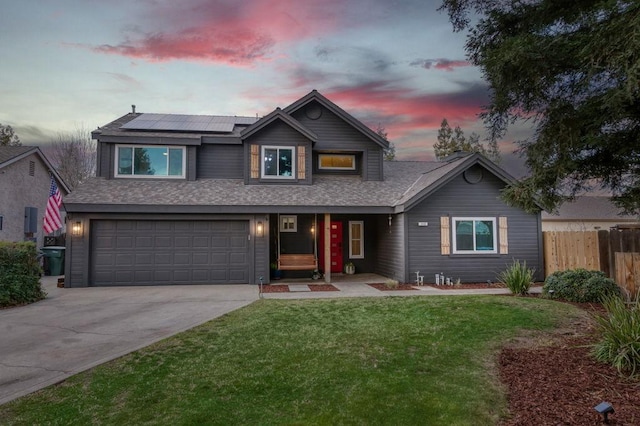 traditional-style house with solar panels, fence, concrete driveway, a front yard, and a garage