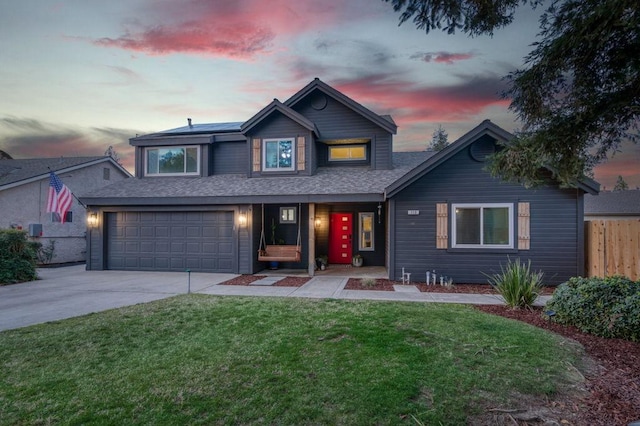 traditional-style home with a front lawn, driveway, fence, roof with shingles, and an attached garage