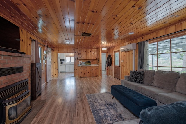 living area featuring a wall mounted AC, plenty of natural light, wood finished floors, and visible vents