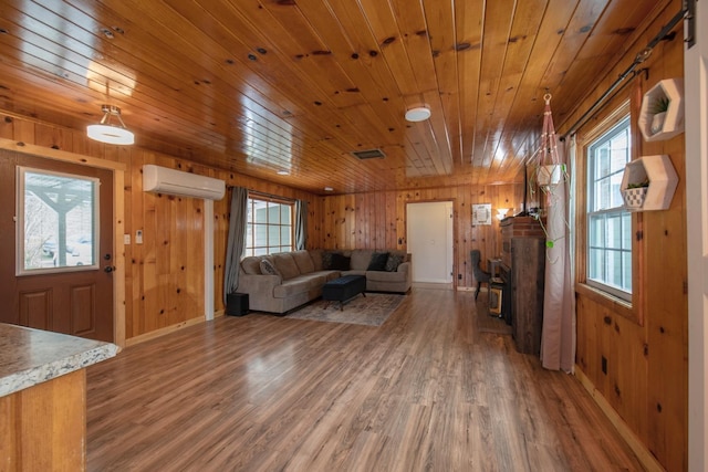 unfurnished living room with a wall mounted AC, wood finished floors, and a healthy amount of sunlight