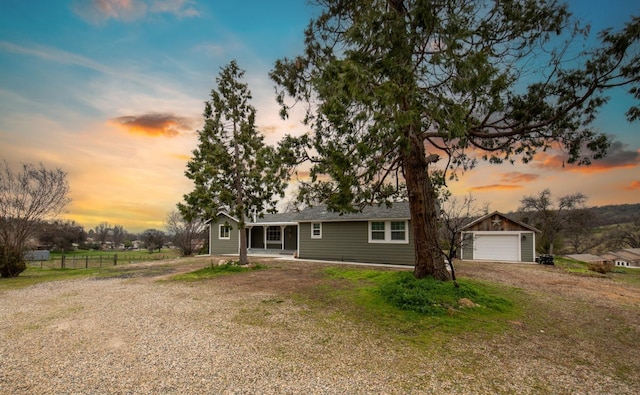 view of front of property featuring an outbuilding, a front yard, fence, a garage, and driveway