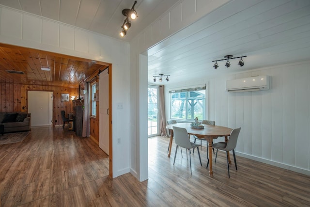 dining space featuring wood finished floors, rail lighting, and a wall mounted AC