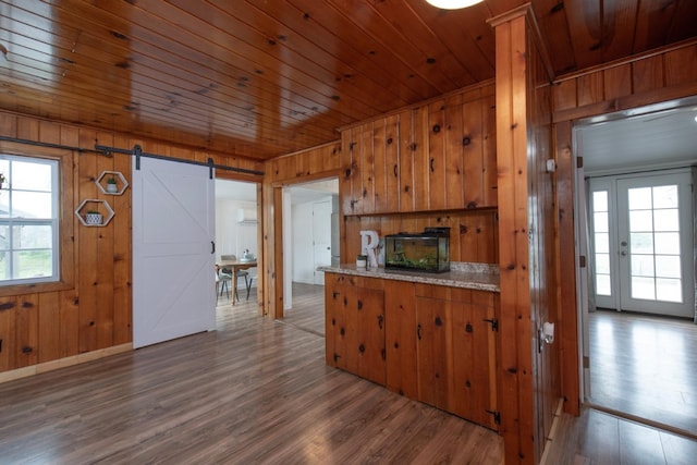 kitchen featuring dark wood-style flooring, light countertops, a barn door, wood ceiling, and wood walls