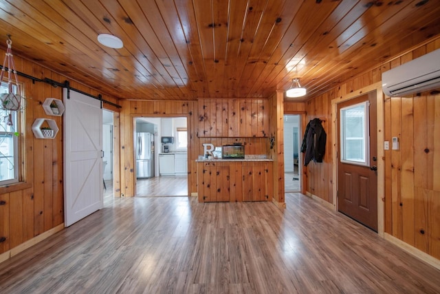 kitchen featuring a barn door, a wall unit AC, wood finished floors, light countertops, and freestanding refrigerator