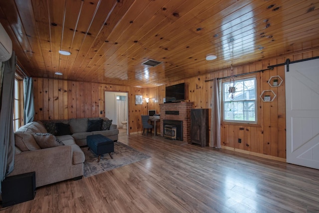 living room with wood ceiling, wood finished floors, a fireplace, and a barn door