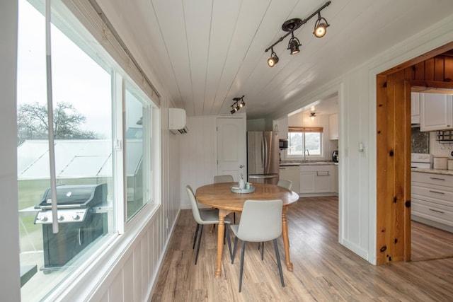 dining space with track lighting, wood ceiling, a wall mounted air conditioner, and light wood finished floors