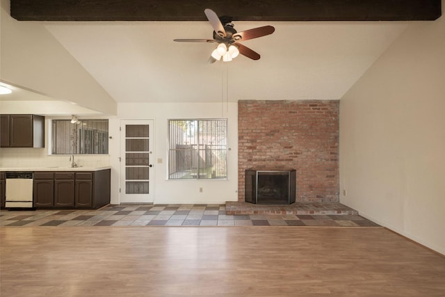 unfurnished living room featuring lofted ceiling with beams, ceiling fan, wood finished floors, a brick fireplace, and a sink