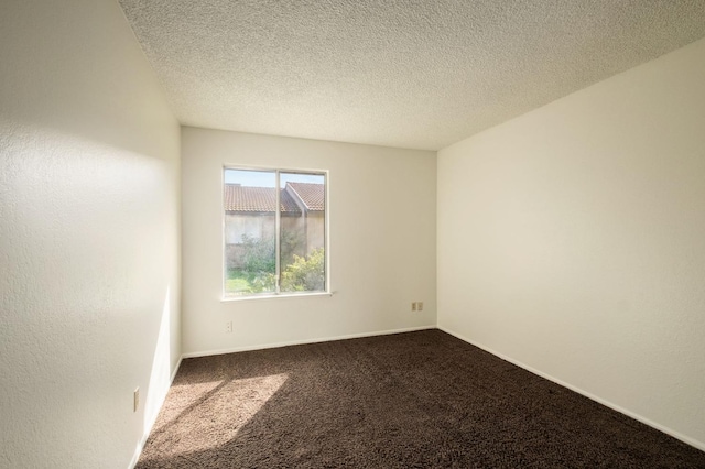 carpeted empty room with a textured ceiling and baseboards