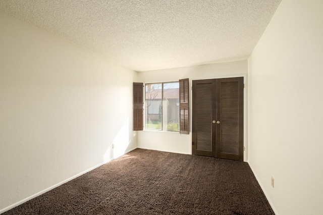 spare room featuring carpet, a textured ceiling, and baseboards