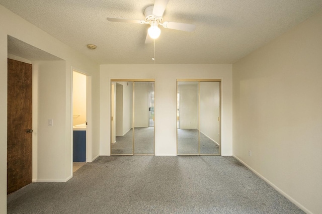 unfurnished bedroom featuring a textured ceiling, baseboards, two closets, and light colored carpet