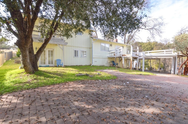 back of property with decorative driveway, french doors, a lawn, and a carport