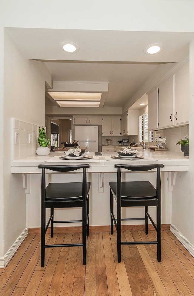 kitchen with light countertops, a peninsula, and freestanding refrigerator