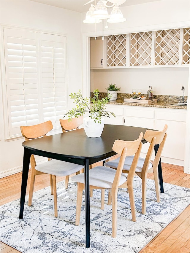 dining space with baseboards, light wood-style flooring, and wet bar