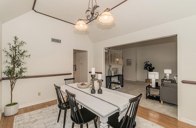 dining space with lofted ceiling, baseboards, visible vents, and wood finished floors