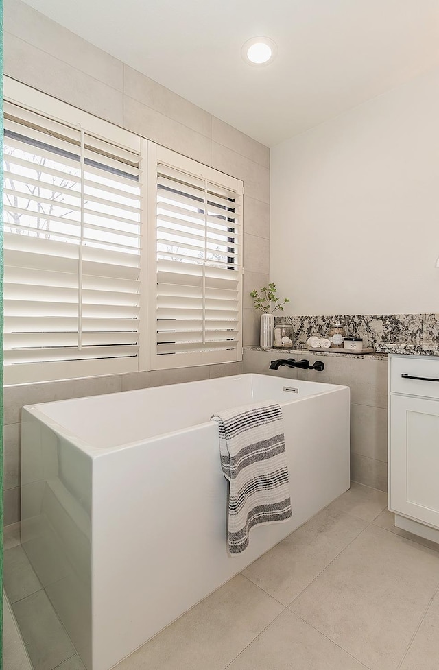 full bathroom featuring a freestanding bath, tile walls, and tile patterned floors