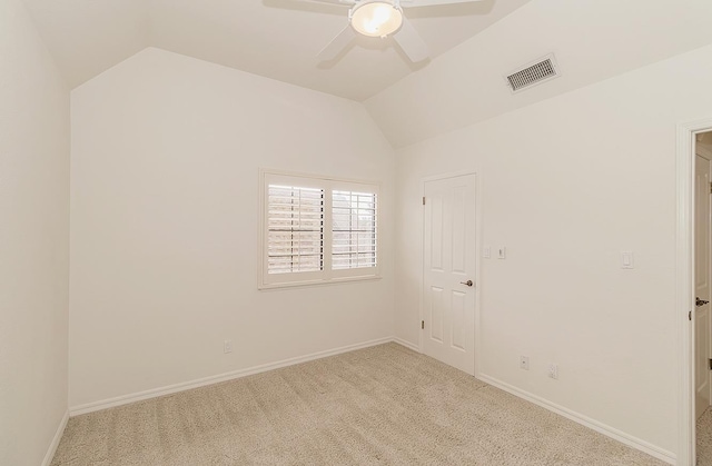 spare room with lofted ceiling, baseboards, light carpet, and visible vents