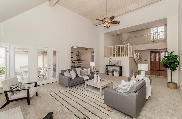 living area with high vaulted ceiling, beam ceiling, light carpet, and stairway