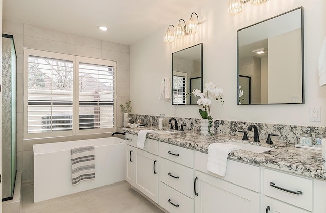 bathroom featuring tile patterned floors, a sink, a freestanding bath, and double vanity