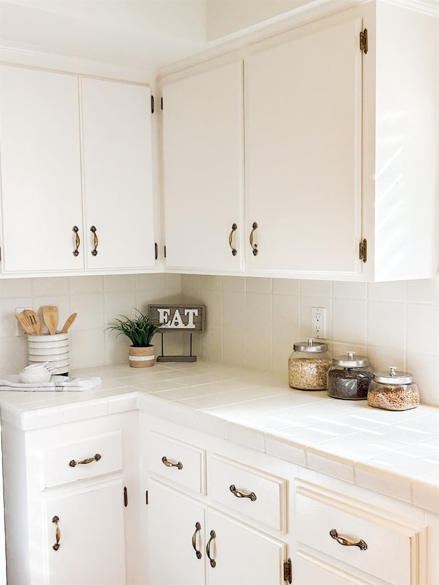 interior space featuring white cabinets, tile countertops, and decorative backsplash