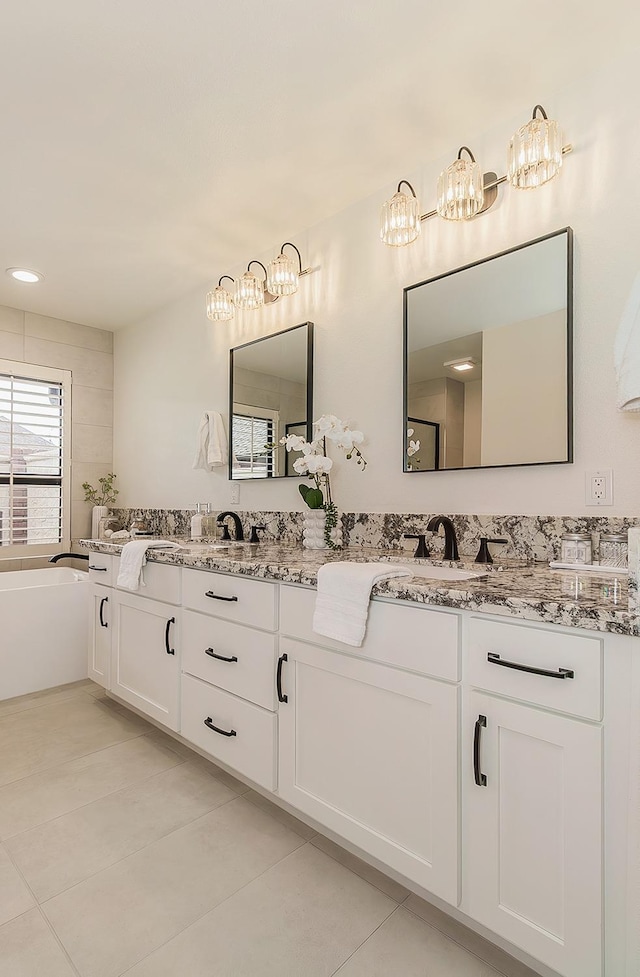 bathroom with double vanity, a soaking tub, tile patterned flooring, and a sink